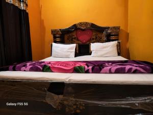 a bed with purple sheets and a heart headboard at DIOMAND HOTEL AND RESTURENt in Bilgrām