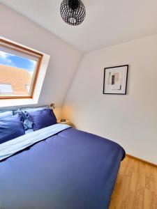 a bedroom with a blue bed and a window at Cosy Corner 4 in Nieuwpoort