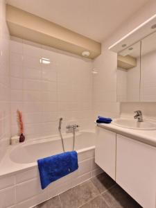 a white bathroom with a tub and a sink at Cosy Corner 4 in Nieuwpoort