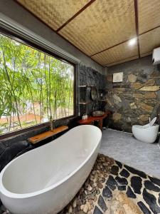 eine große Badewanne in einem Badezimmer mit Steinwand in der Unterkunft Coconut Minh Tho Homestay in Mai Châu