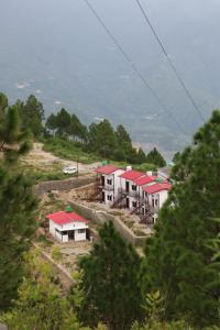 un groupe de bâtiments aux toits rouges sur une colline dans l'établissement Tathastu Resort Tehri By Royal Collection Hotels, à Tehri-Garhwāl
