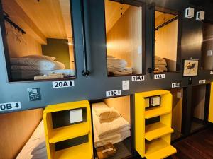 a room with three bunk beds and yellow shelves at Otemachi Kamon Hotel in Tokyo