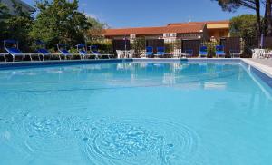 a large blue swimming pool with chairs and tables at Hotel Lilly in Marina di Campo