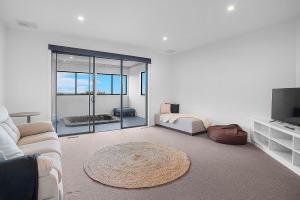 a white living room with a couch and a television at Mornington Esplanade Beachfront & Spa by RSS in Mornington
