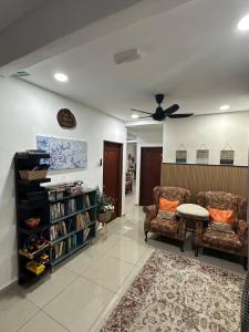 a living room with two chairs and a ceiling fan at AliyaRoseMuslim Homestay in Ayer Keroh