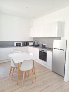 eine Küche mit weißen Schränken sowie einem weißen Tisch und Stühlen in der Unterkunft AquaLodge Serena in Aix-les-Bains