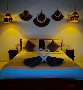 two swans are forming a heart on a bed at Hillside bali in Kubupenlokan