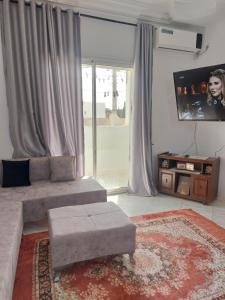 a living room with a couch and a tv at Location saisonnière un salon et deux chambres in Raʼs al Jabal