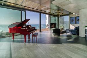 a red piano in a living room with a view of the ocean at Hayarkon Apartment By the Sea in Tel Aviv +1 photo