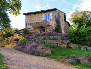 a house on a hill with purple flowers in front of it at Castel Mazars in Castelnau-de-Montmiral