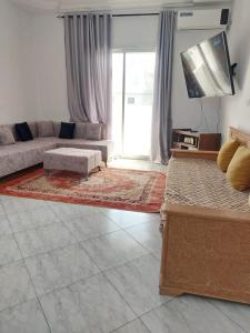 een woonkamer met een bank en een tv bij Location saisonnière entre mer, forêt et calme in Raʼs al Jabal