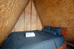 クブペンロカンにあるAnd Dita Glampingの籐の屋根が付いたベッドのある寝室