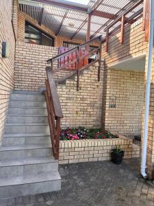 a brick building with a staircase and flowers at Pladda in Plett in Plettenberg Bay
