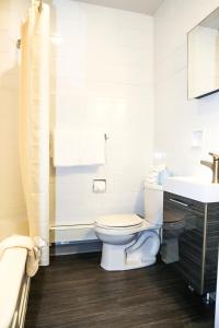 La salle de bains blanche est pourvue de toilettes et d'un lavabo. dans l'établissement Cadillac Motel Niagara, à Niagara Falls