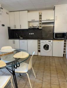 勒普拉代Appartement Hélène 200m plage, piscine et terrain de tennis的厨房配有白色橱柜、桌子和洗衣机。 更多12张照片