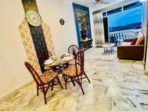 a dining room with a table and chairs and a clock at GloryBeachResort2BedroomWifiNetflixFreeparking in Port Dickson