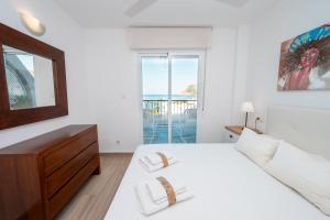 Dormitorio blanco con cama y vistas al océano en Rincón de la Caleta, en La Herradura