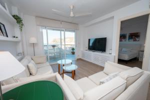 Una sala de estar con muebles blancos y un televisor de pantalla plana. en Rincón de la Caleta, en La Herradura