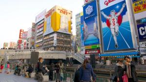 una multitud de personas caminando en una ciudad con edificios en 民泊悠, en Osaka