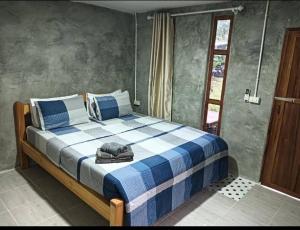 a bedroom with a bed with a blue and white blanket at Uncle peiyk homestay in Ban Bang Bao