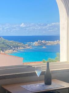 a wine glass sitting on a table next to a window at Giulia Suite Sea View in Santa Teresa Gallura