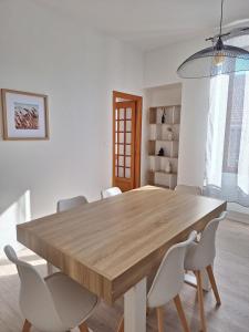 a dining room with a wooden table and white chairs at AquaLodge Vitalia in Aix-les-Bains +6 photos