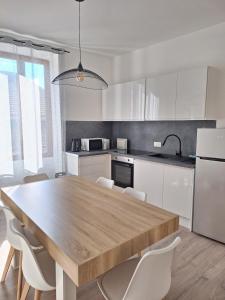 a kitchen with a wooden table and white cabinets at AquaLodge Vitalia in Aix-les-Bains