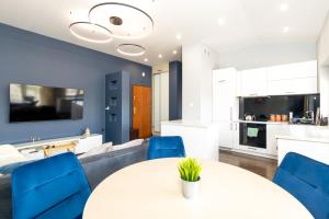 a kitchen and living room with a white table and blue chairs at Tabago Studio 39 Skierniewice in Skierniewice