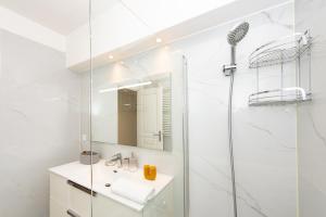a white bathroom with a shower and a sink at Hypercentre - Spacieux trois pièces rénové - EG in Beausoleil +21 photos