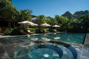 una piscina con sedie e ombrelloni in un resort di Nham Village Resort a Ninh Binh