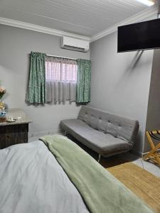 una sala de estar con una cama y un sofá en The Hideaway Guesthouse, en Groblersdal