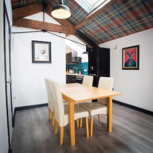 a dining room with a wooden table and white chairs at The Coach House by The Hive WA1 in Warrington