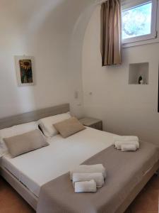ein weißes Bett mit zwei Handtüchern darauf in der Unterkunft Trullo il Gelso with Private Salt Water Infinity Pool and Jacuzzi inside in San Michele Salentino + 75 Fotos
