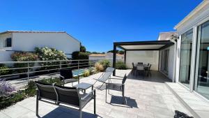 Un patio con sillas y mesas en un balcón. en Superbe villa avec piscine chauffée, proche mer, en Ars-en-Ré