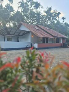 a house with red flowers in front of it at Cabana banasura Wayanad 2bhk in Padinjarathara
