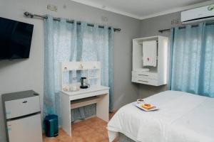 a bedroom with a bed and a table and a tv at One Apartment in Gaborone
