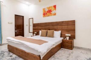 ジャイプールにあるStylish & Cozy Retreat With Jacuzziの木製のヘッドボードが付いた大きなベッドのある寝室