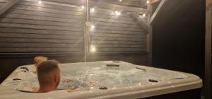 a man sitting in a bath tub with a shower at Śpij-tu Twój dom wypoczynkowy na szlaku wielkich jezior in Mikołajki