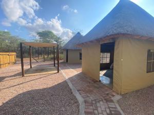 un edificio con techo de paja con un parque infantil en Vlakvark Tented Camp, en Bela-Bela