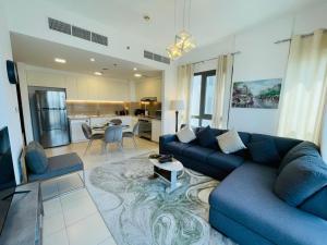Nadd ShubayḩにあるTown Square Zahra 2B - 2 Bedroom Apartment - Allsopp & Allsoppの青いソファとキッチンのあるリビングルーム
