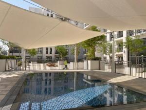 Nadd ShubayḩにあるTown Square Zahra 2B - 2 Bedroom Apartment - Allsopp & Allsoppの建物の前に傘付きのスイミングプール