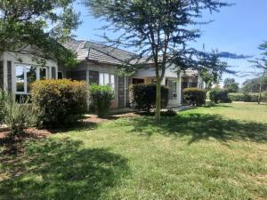 a house with a grass yard in front of it at Cobbs in Nanyuki