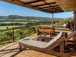 a deck with a bench and a table and chairs at Howberry Hills in Plettenberg Bay +5 photos