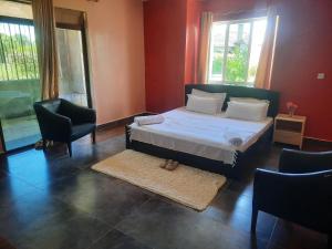 a bedroom with a bed and two chairs and windows at Cobbs in Nanyuki