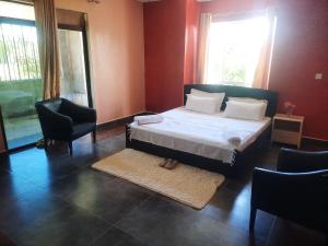 a bedroom with a bed and two chairs at Cobbs in Nanyuki +15 photos