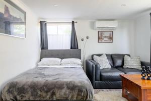 a bedroom with a bed and a couch at Enjoy your home away from home in Rooty Hill