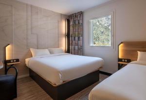 a hotel room with two beds and a window at B&B HOTEL Mâcon Sud 3 étoiles in Varennes-lès-Mâcon