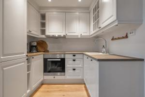 a white kitchen with white cabinets and a sink at Northstay - Town Square in Tromsø +11 photos