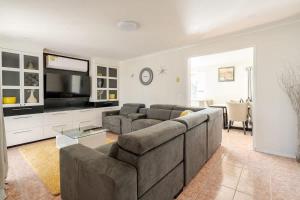 a living room with a couch and a flat screen tv at Beautiful and Colourful House with Parking in Rooty Hill