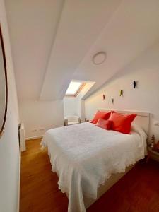 una camera da letto con un grande letto bianco con cuscini rossi di Finisterre Aloha a Fisterra (Finisterre)